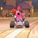 Birdo waves while driving a kart.