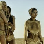 Scantly clad women in Mad Max: Fury Road stare out at something beyond the camera.