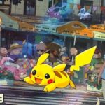 Pikachu running through a street with trainers and Pokemon around.