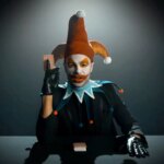 A man in a clown outfit plays with cards.