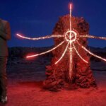 Geoff Keighley stands next to a demonic statue.