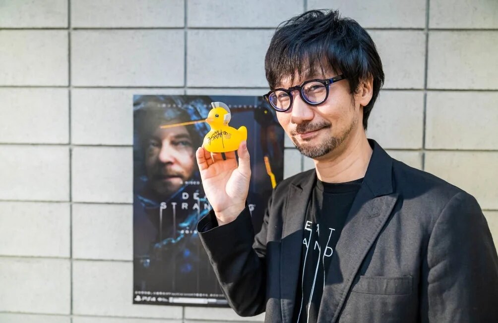 Kojima holds up a rubber ducky.