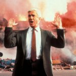 A man holds up his hands as things explode.