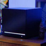 A Steam Machine sits on a desk with an action figure.